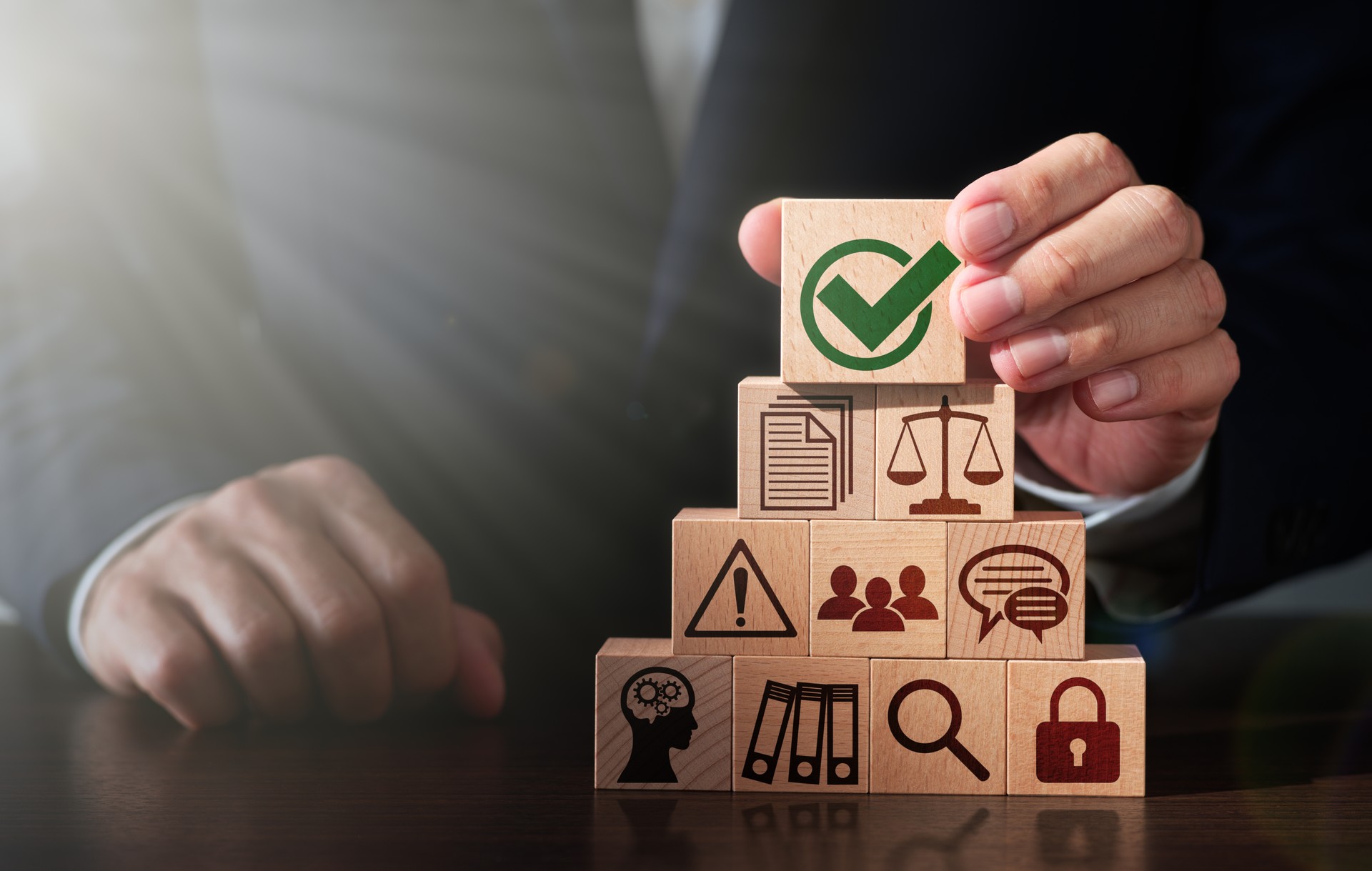 Regulatory compliance and business management. Businessman stacking wooden blocks.